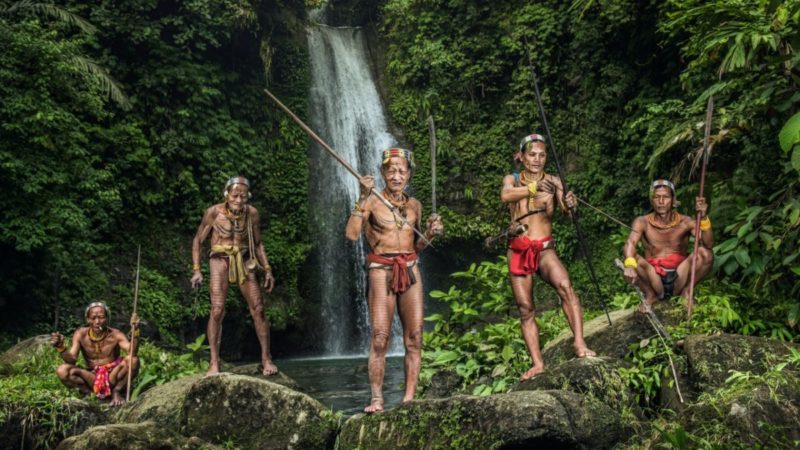 Group of Mentawai tribesman with spears bows and arrows in front of a waterfall in Sumatra Indonesia
