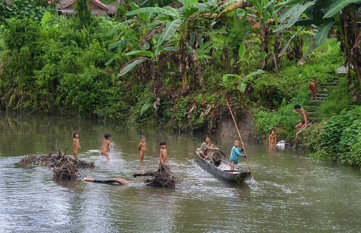 Indonesian Sumatra Mentawai tribesmen on canoes in a river