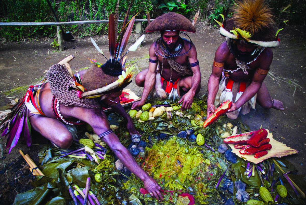 Hobres de la tribu huli de Papúa Nueva Guinea cocinando al estilo mumu